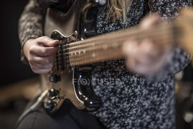 Primer plano de la mujer tocando la guitarra eléctrica - foto de stock