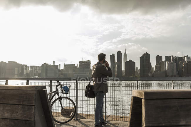 USA, New York City, Geschäftsmann am East River am Handy — Stockfoto