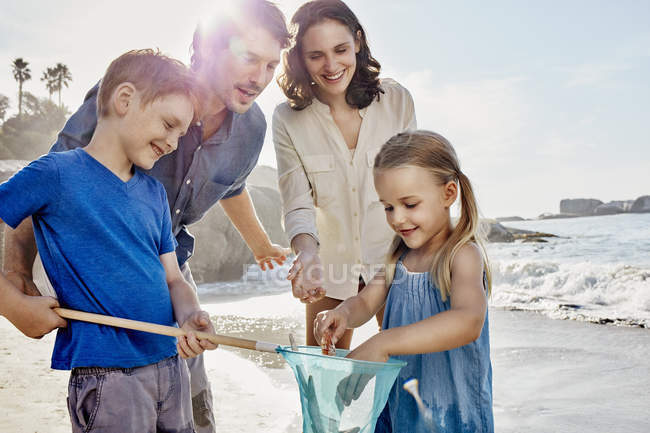 Famiglia felice con rete da immersione sulla spiaggia — Foto stock