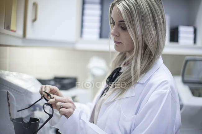 Opticien femelle regardant la monture de lunettes — Photo de stock