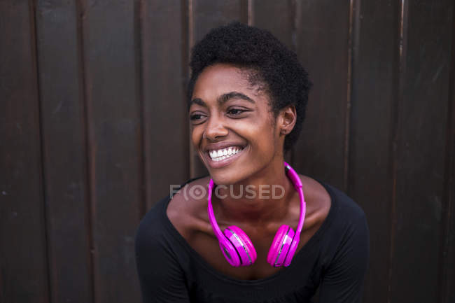 Jeune femme afro-américaine souriante avec écouteurs violets — Photo de stock