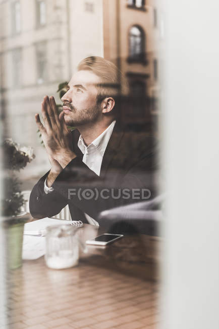 Giovane uomo d'affari che pensa in un caffè dietro il vetro della finestra — Foto stock