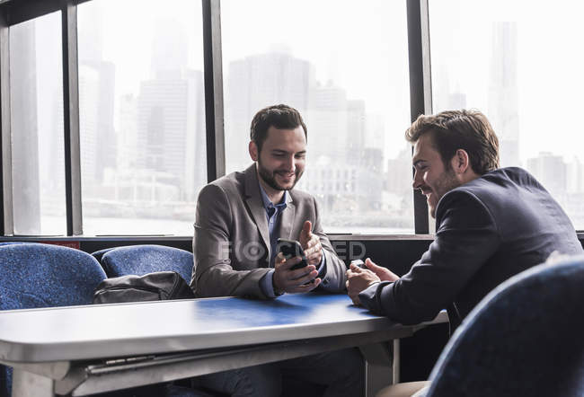 Двоє бізнесменів, що використання мобільників пасажирського салону порому — стокове фото