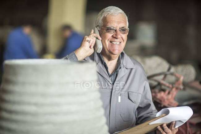 Человек с планшетом на телефоне на заводе по производству травки — стоковое фото