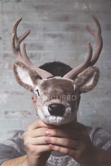 Young man holding artificial deer head in front of his face — unusual,  caucasian - Stock Photo | #177768838