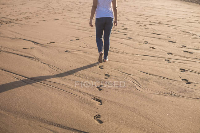 Donna che cammina nella sabbia sulla spiaggia a piedi nudi — Foto stock
