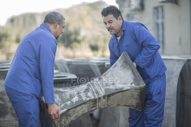 Deux hommes portant des objets céramiques à l'usine de pots industriels — Photo de stock