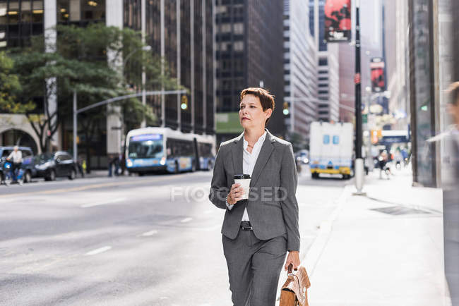 Businesswoman walking in Manhattan with takeaway coffee, USA, New York — Stock Photo