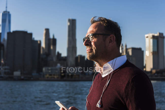 USA, Brooklyn, homme d'affaires avec smartphone et écouteurs au soleil — Photo de stock