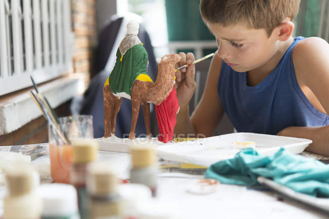 Boy painting nativity figurines — Stock Photo