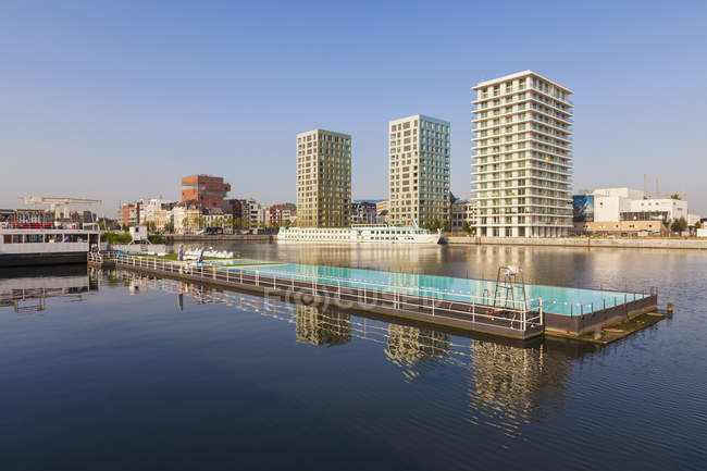 Bélgica, Flandes, Amberes, antigua zona portuaria, piscina, edificios de apartamentos contra el agua - foto de stock
