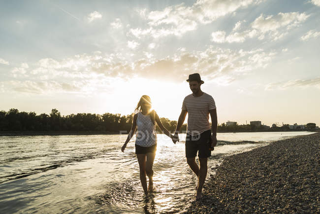 Pareja caminando de la mano a la orilla del río al atardecer — noche, Relajado - Stock Photo | #178095210 Pareja caminando de la mano a la orilla del río al atardecer — noche, Relajado - Stock Photo | #178095210