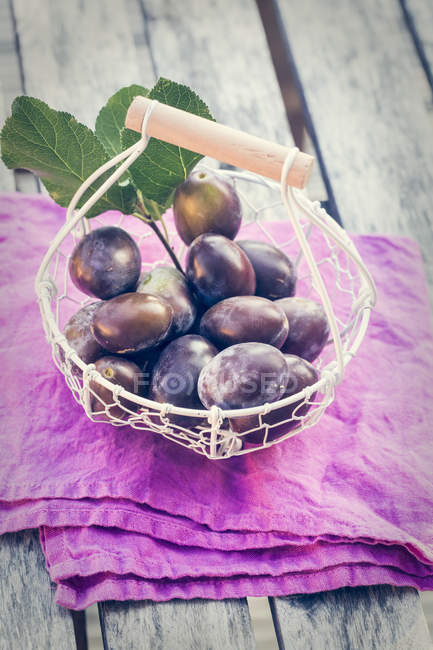 Wire basket of fresh plums — Stock Photo