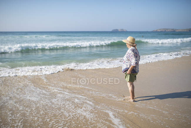 Espagne, Ferrol, femme âgée debout sur la plage regardant de loin — Photo de stock