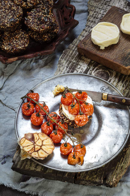Смажені помідори, кростіні з козячим сиром і часник на тарілку — стокове фото