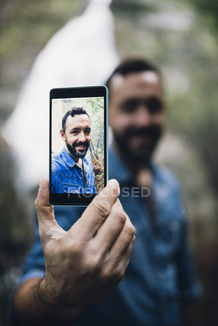 Hombre barbudo mostrando selfie en la pantalla de su teléfono inteligente - foto de stock