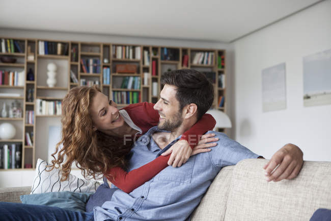 Щаслива жінка обіймає чоловіка на дивані — стокове фото