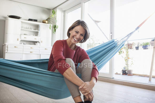 Femme heureuse à la maison assise dans un hamac — Photo de stock