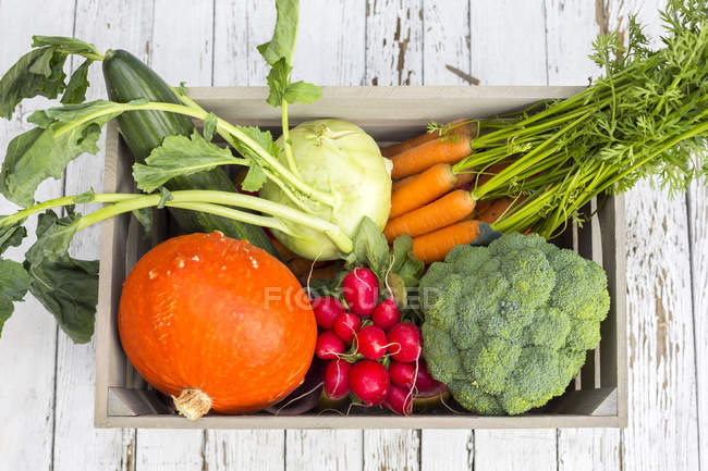 Boîte en bois de différents légumes frais cueillis — Photo de stock