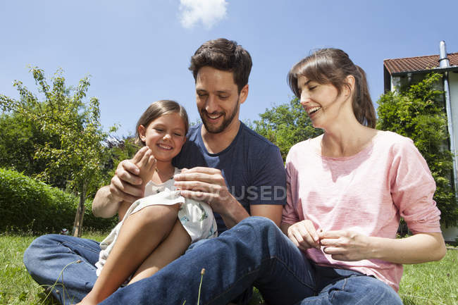 Família caucasiana feliz com filha no jardim — Fotografia de Stock