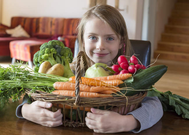 Ritratto di ragazza sorridente con cesto di vimini di verdure fresche a casa — Foto stock