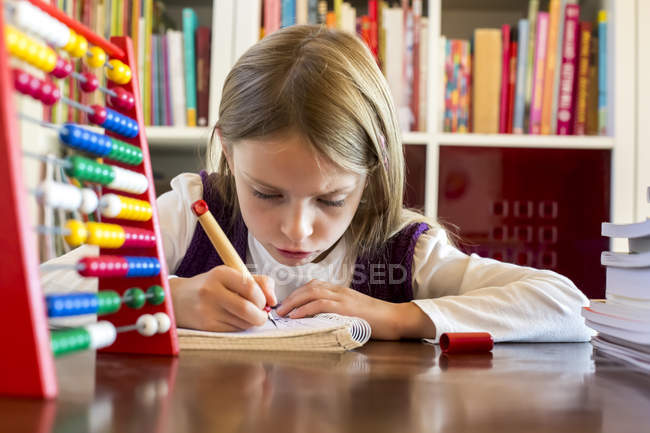 Ritratto di ragazza che fa i compiti a tavola — Foto stock