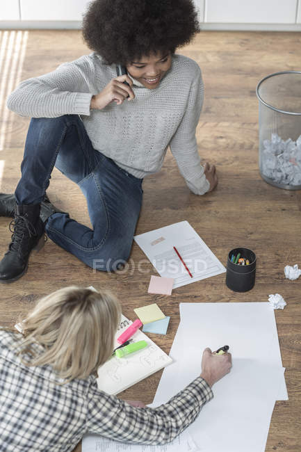 Two colleagues with papers on office floor — Stock Photo