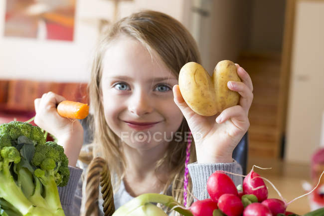 Ritratto di ragazza sorridente che mostra patate e carote sorridenti alla macchina fotografica — Foto stock