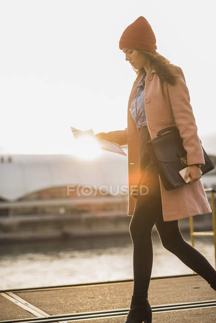 Молода жінка, йдучи на березі річки переглядають документ — стокове фото