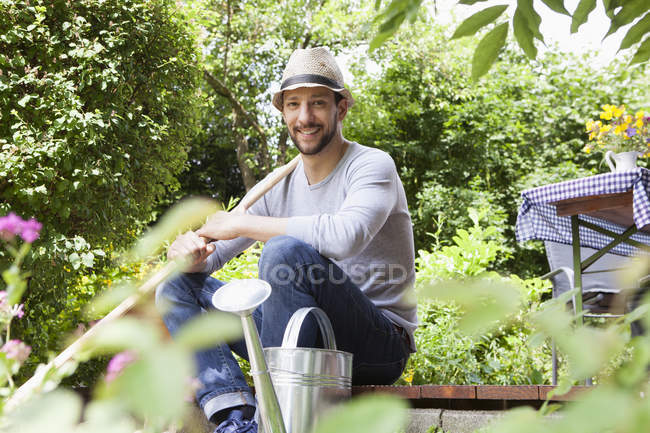 Улыбающийся взрослый кавказский мужчина сидит на террасе в саду — стоковое фото