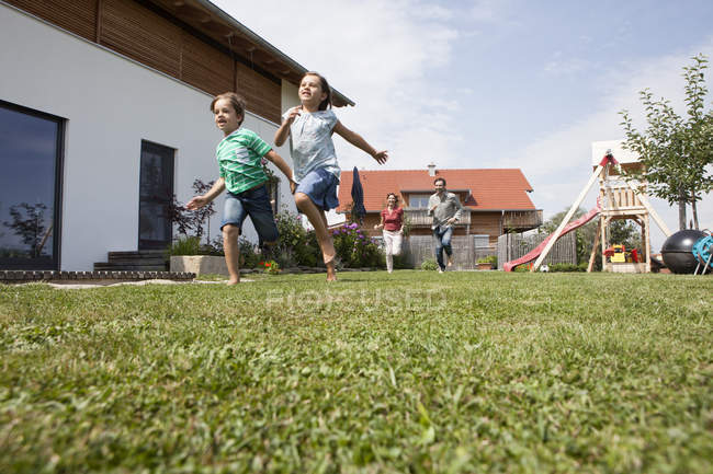 Família caucasiana despreocupada correndo no jardim — Fotografia de Stock