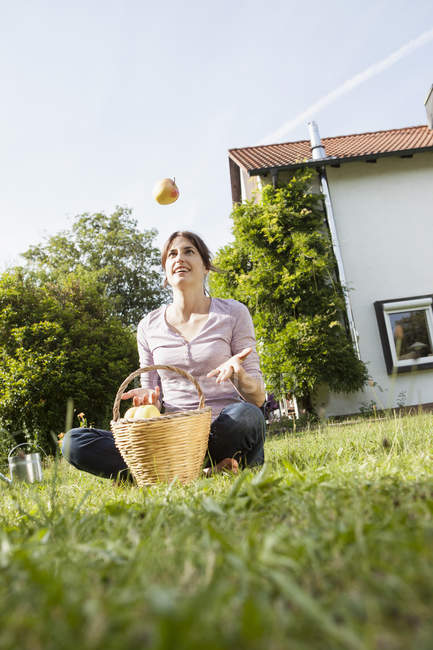 Усміхається жінка, сидячи в саду вирвало apple — стокове фото