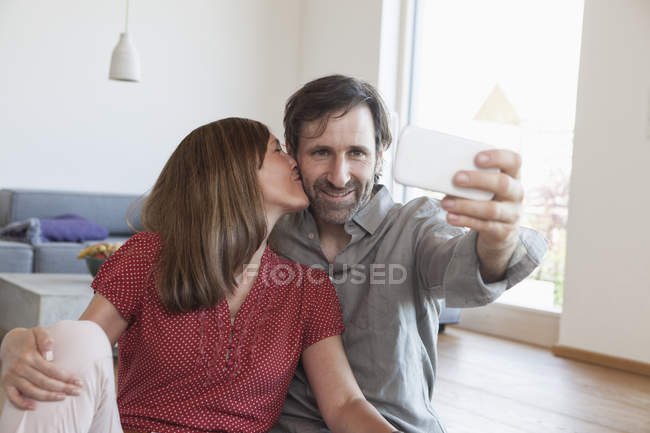 Літня пара, сидячи на підлозі, беручи selfie зі смарт-телефон — стокове фото