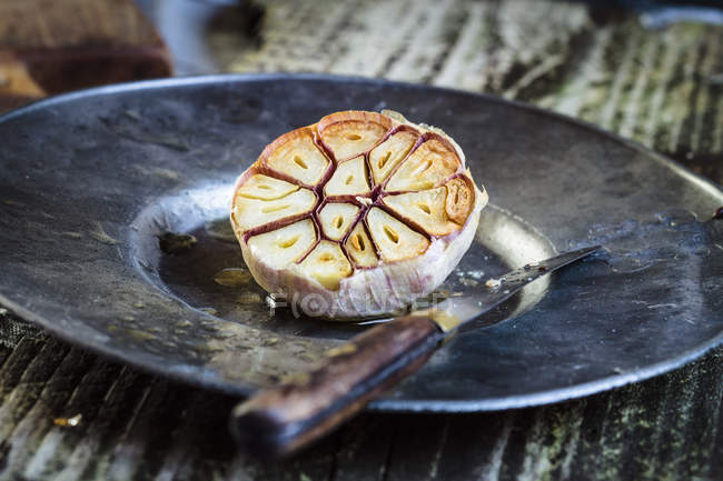 Vista ravvicinata dell'aglio arrosto sul piatto con coltello — Foto stock