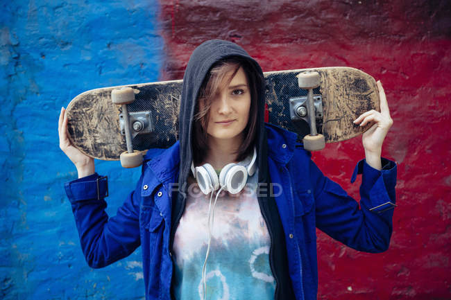 Portrait of young woman holding skateboard — Stock Photo