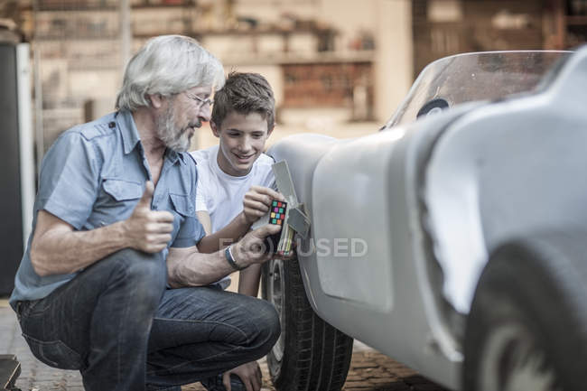 Abuelo y nieto restaurando un coche juntos - foto de stock