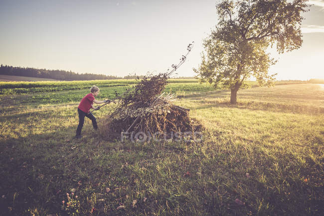 Garçon préparant pile de brindilles et feuilles pour un feu de camp — Photo de stock