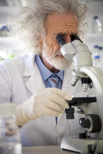 Tousled professor examining samples under microscope — Stock Photo