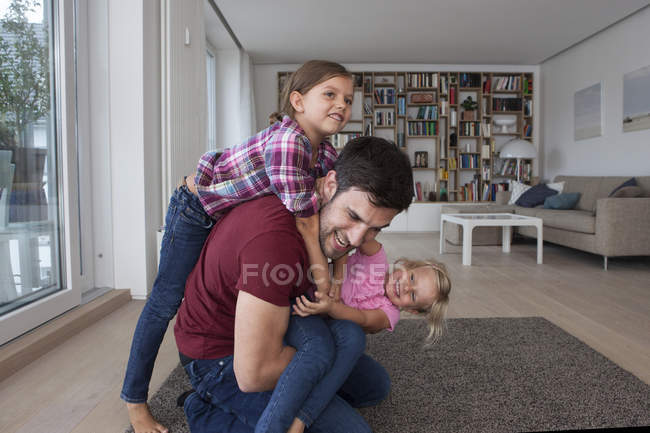 Homem brincando com suas filhas na sala de estar — Fotografia de Stock