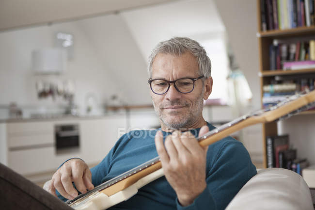 Hombre maduro en casa tocando la guitarra - foto de stock