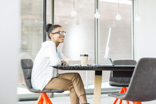 Smiling young woman sitting  in office — Stock Photo