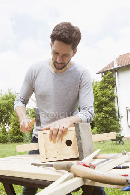 Adulto caucasico uomo timbering un birdhouse — Foto stock
