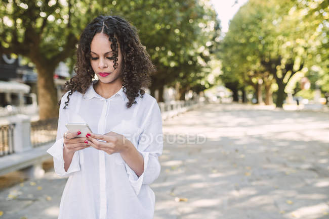 Femme utilisant un smartphone dans le parc — Photo de stock