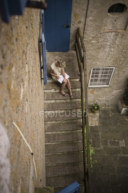 Italia, Toscana, Donna seduta sulle scale di una casa di campagna, disegnando un quadro — Foto stock