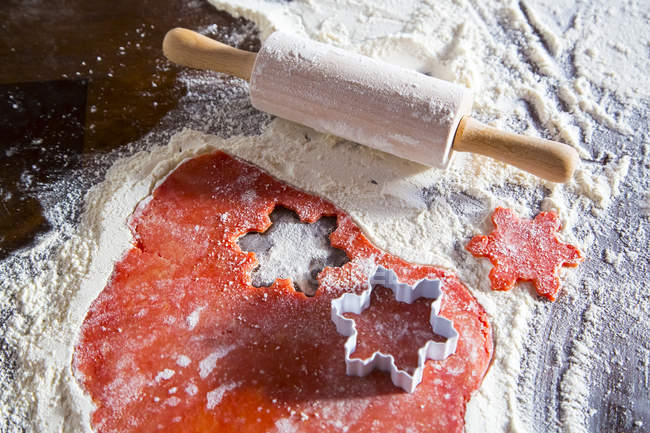 Christmas bakery with red dough with rolling pin — Stock Photo