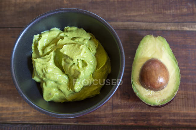 Schüssel Guacamole und die Hälfte der Avocado — Stockfoto