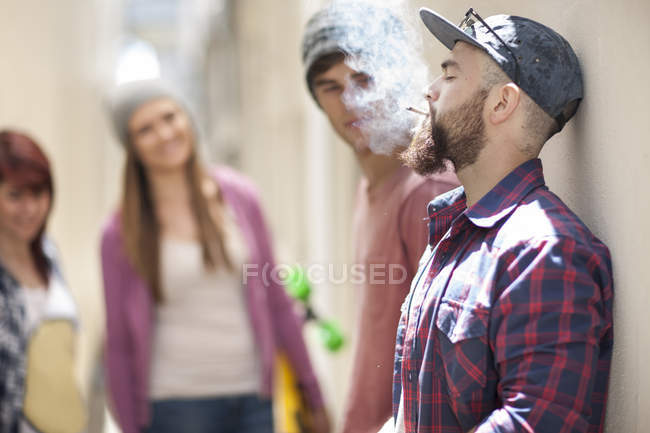 Giovane uomo fumare una sigaretta con gli amici in background — Foto stock