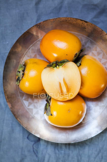 Closeup view of sliced and whole kaki on metal plate — Stock Photo