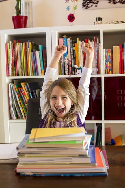 Portrait of cheering girl sitting behind stack of books — Stock Photo
