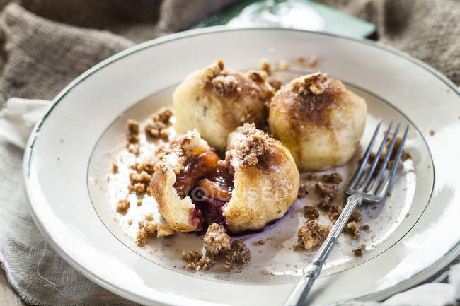 Potato dumplings filled with plums, cinnamon, sugar and nuts on plate — Stock Photo